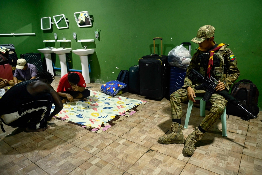 In this photo taken on February 23, 2025 a member of the Karen Border Guard Force (BGF) guards alleged scam centre workers and victims during a crackdown operation by the Karen Border Guard Force (BGF) on illicit activity, at the border checkpoint with Thailand in Myanmar's eastern Myawaddy township. — AFP pic 