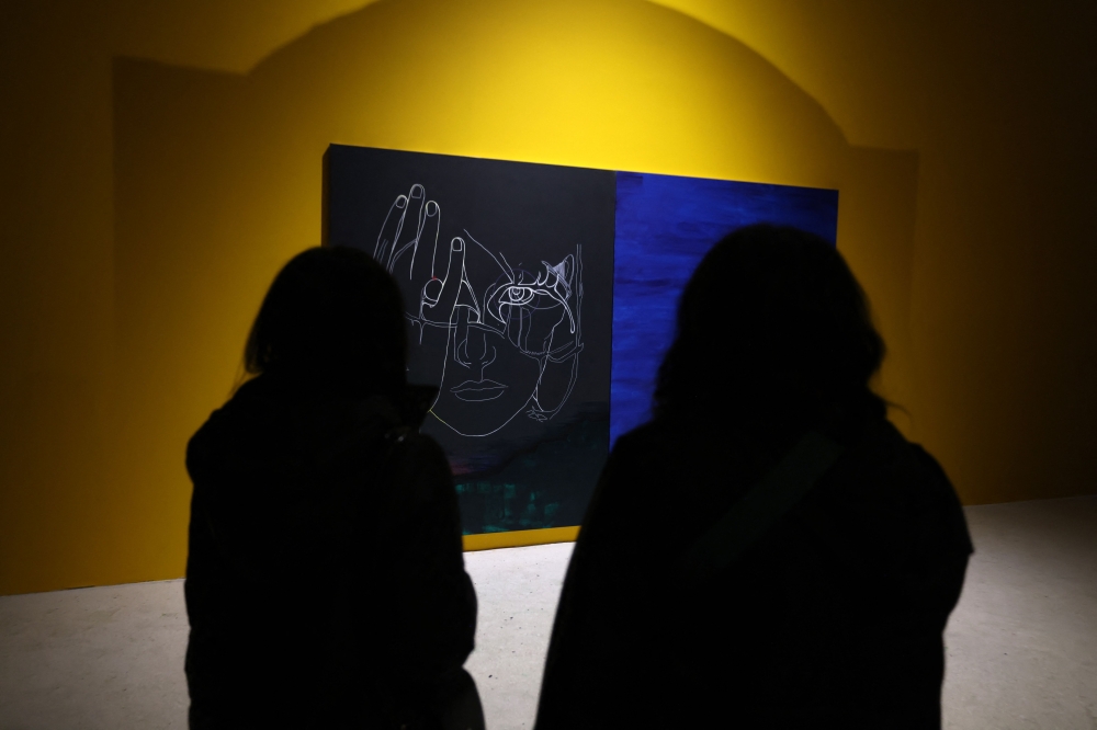 Women look at a painting , part of a multimedia exhibition by Iranian artist Mimi Amini at the Argo Factory, a contemporary art museum and cultural centre, housed in a former brewery in Tehran, on February 5, 2025. — AFP pic